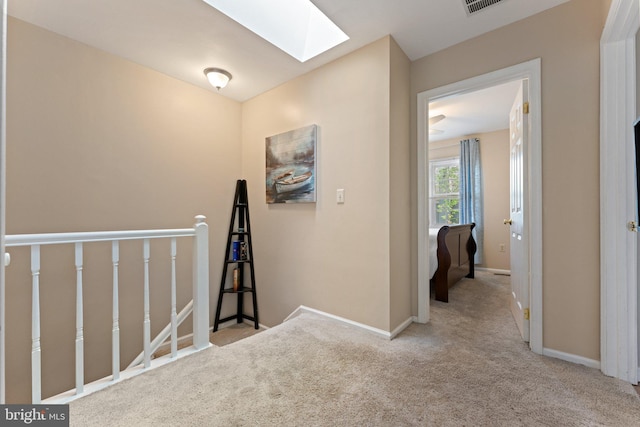 corridor featuring baseboards, carpet floors, an upstairs landing, and a skylight