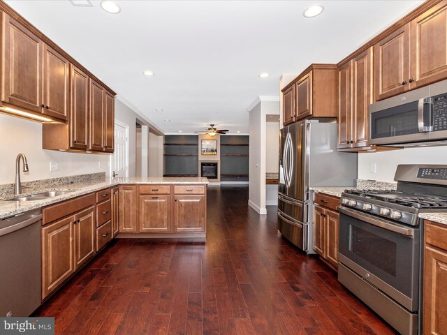 kitchen with stainless steel appliances, a peninsula, dark wood-style floors, a sink, and ceiling fan