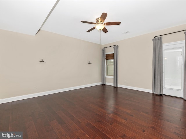spare room featuring dark wood finished floors, visible vents, a ceiling fan, and baseboards