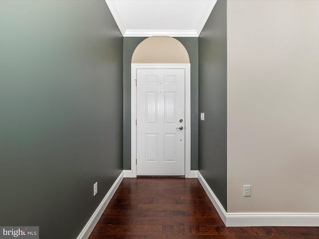 doorway featuring baseboards, crown molding, and wood finished floors