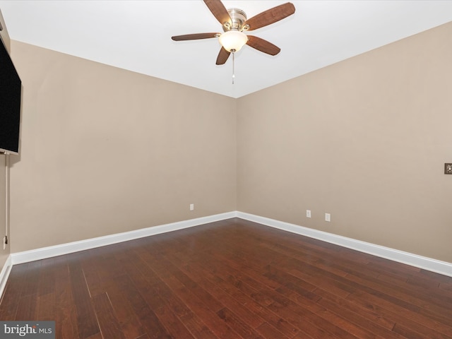 empty room with dark wood finished floors, a ceiling fan, and baseboards