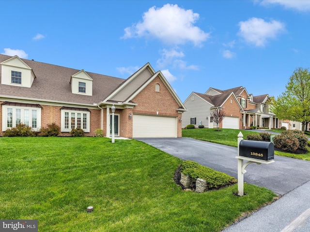 view of front of property with a front lawn, driveway, a shingled roof, an attached garage, and brick siding