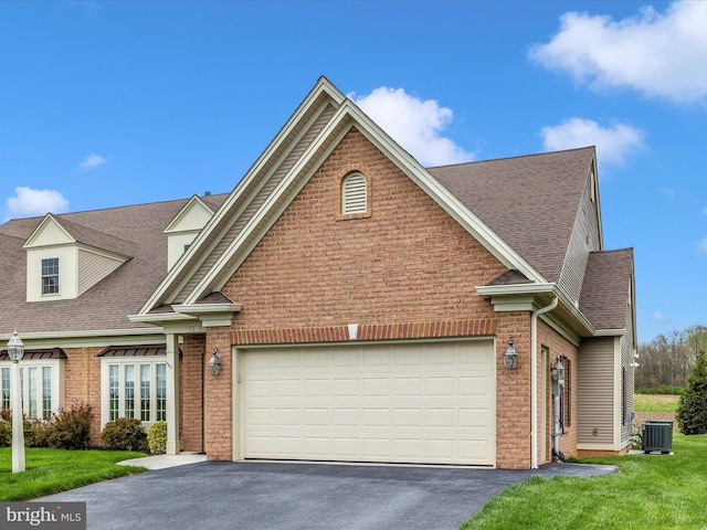 view of front of property with central air condition unit, driveway, an attached garage, brick siding, and roof with shingles