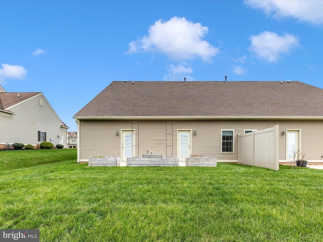 back of house featuring a shingled roof and a yard