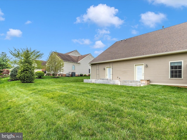 back of house featuring a yard and a shingled roof