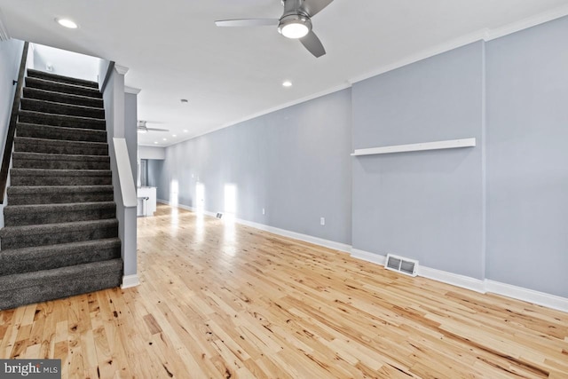 unfurnished living room with visible vents, ornamental molding, ceiling fan, and stairs
