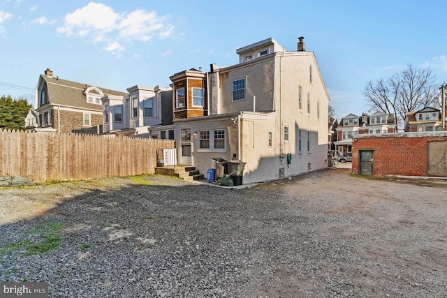 back of house featuring a residential view, stucco siding, and fence