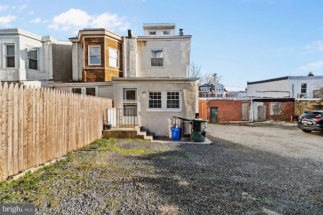 rear view of house featuring stucco siding and fence