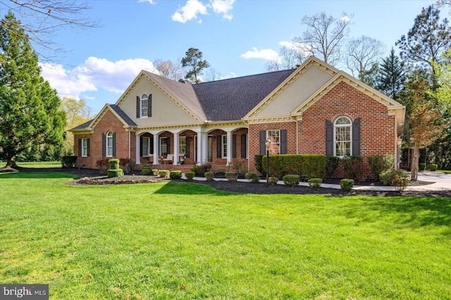 view of front facade featuring a porch, a front lawn, brick siding, and roof with shingles