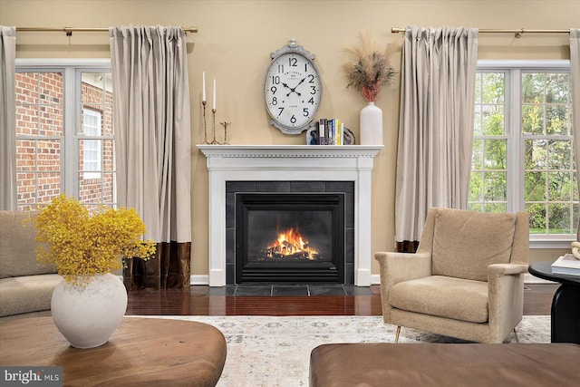 sitting room featuring a tiled fireplace and wood finished floors
