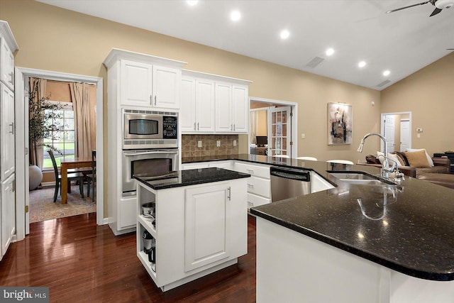 kitchen featuring dark wood-style floors, stainless steel appliances, a sink, a center island, and decorative backsplash