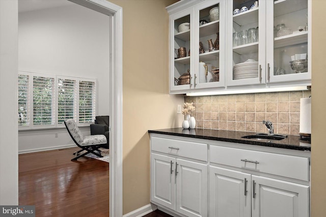 bar featuring baseboards, a sink, tasteful backsplash, and dark wood-style flooring