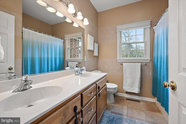 full bathroom with a sink, double vanity, toilet, baseboards, and visible vents