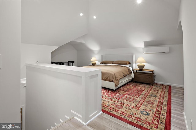 bedroom with a wall mounted air conditioner, lofted ceiling, baseboards, and wood finished floors