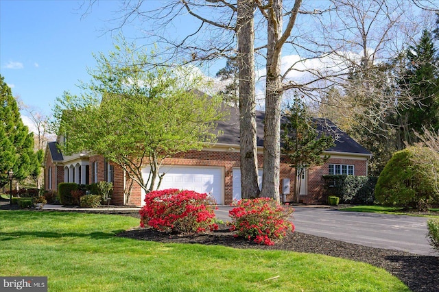 obstructed view of property featuring brick siding, an attached garage, aphalt driveway, and a front yard