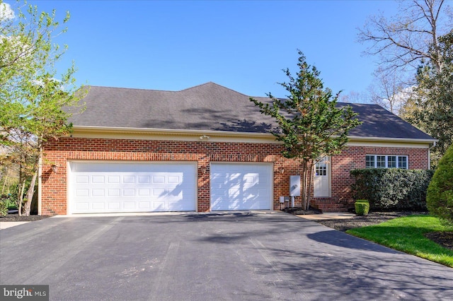 view of front facade featuring brick siding, driveway, a shingled roof, and a garage