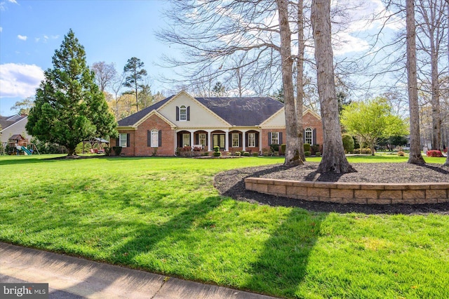 view of front of home with brick siding, a front yard, and a playground