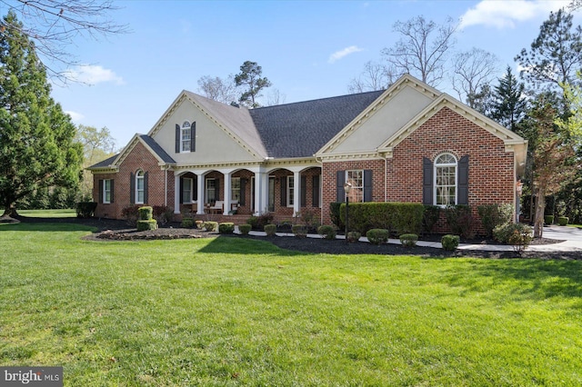 view of front of house featuring brick siding, roof with shingles, a front lawn, and covered porch