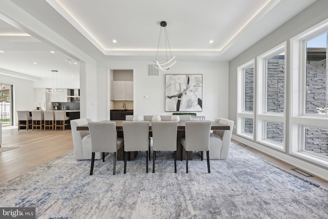 dining room featuring recessed lighting, a raised ceiling, light wood-style flooring, and visible vents