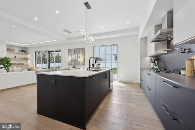kitchen featuring stainless steel gas stovetop, modern cabinets, wall chimney exhaust hood, and a sink
