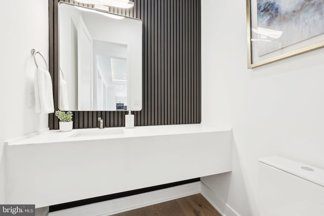 bathroom featuring baseboards, wood finished floors, vanity, and toilet