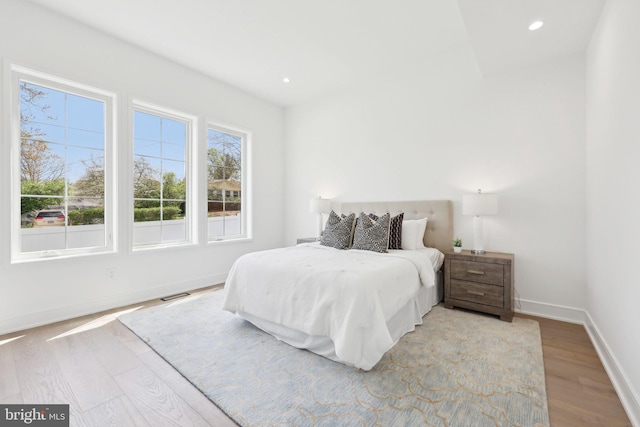 bedroom with baseboards, wood finished floors, visible vents, and recessed lighting