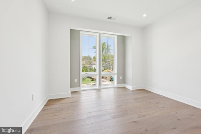 empty room featuring baseboards, light wood-style floors, visible vents, and recessed lighting