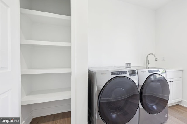 laundry room featuring a sink, cabinet space, washer and clothes dryer, and light wood-type flooring
