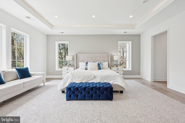 bedroom with baseboards, wood finished floors, a tray ceiling, and recessed lighting