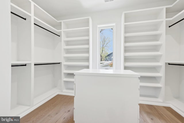 spacious closet with a barn door, light wood-style flooring, and visible vents