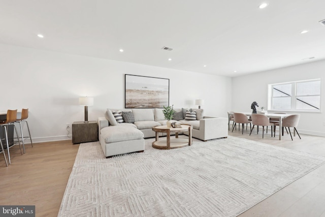 living room featuring recessed lighting, wood finished floors, visible vents, and baseboards