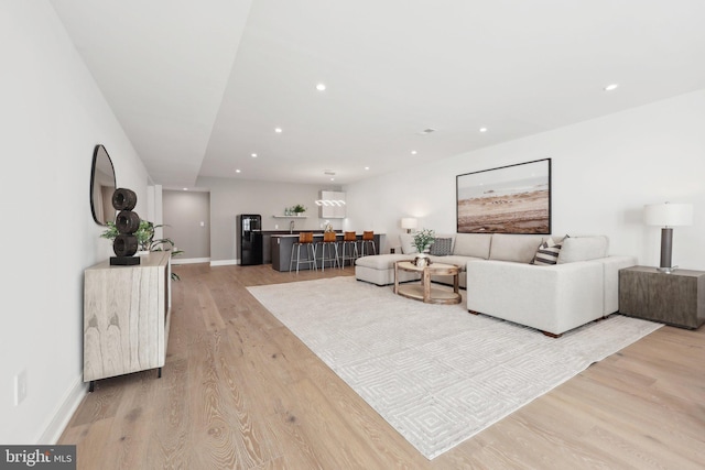 living area featuring recessed lighting, baseboards, and light wood-style flooring