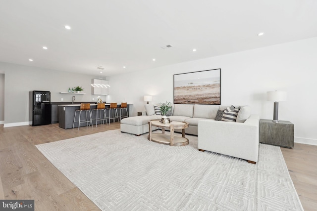 living area with recessed lighting, baseboards, indoor wet bar, and light wood-style flooring