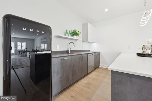 kitchen with a sink, light wood-type flooring, freestanding refrigerator, open shelves, and dishwasher