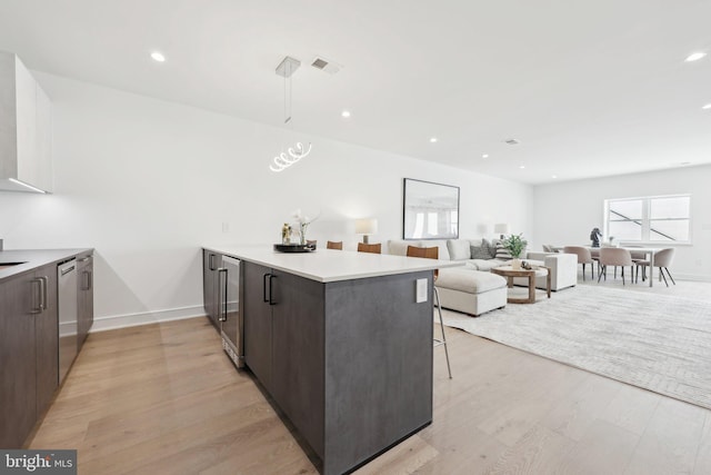 kitchen featuring dishwasher, visible vents, light wood-type flooring, and a breakfast bar area