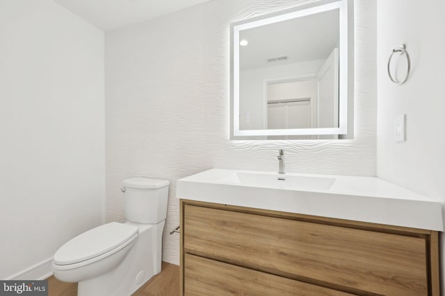 bathroom with wood finished floors, visible vents, vanity, and toilet