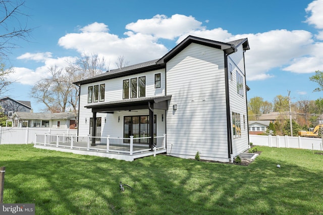 rear view of property featuring ceiling fan, a fenced backyard, and a yard