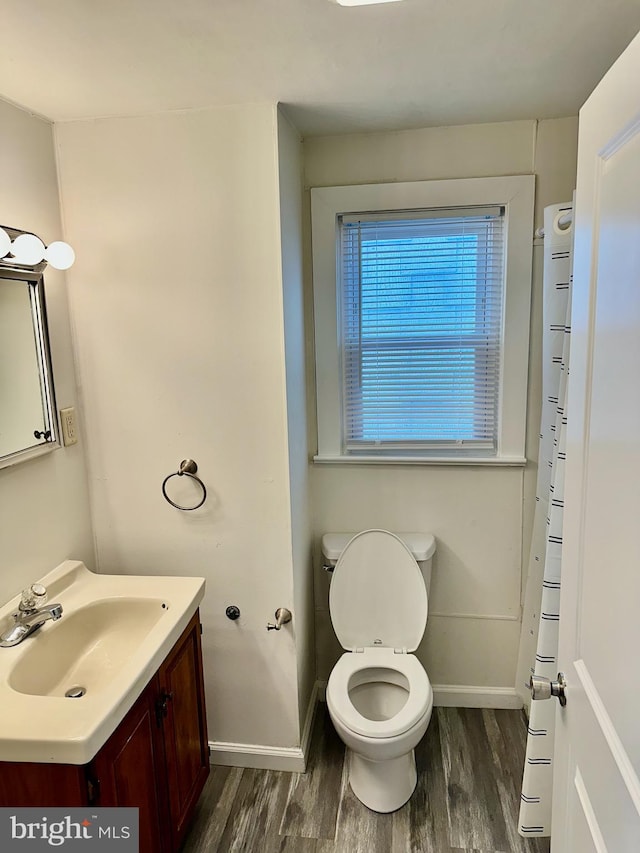 bathroom featuring toilet, vanity, baseboards, and wood finished floors
