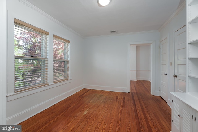 unfurnished room with baseboards, ornamental molding, visible vents, and wood finished floors