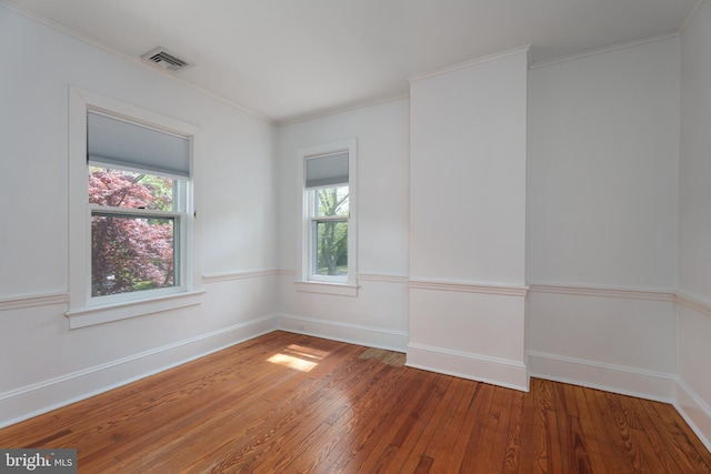 unfurnished room featuring hardwood / wood-style flooring, a wealth of natural light, baseboards, and visible vents
