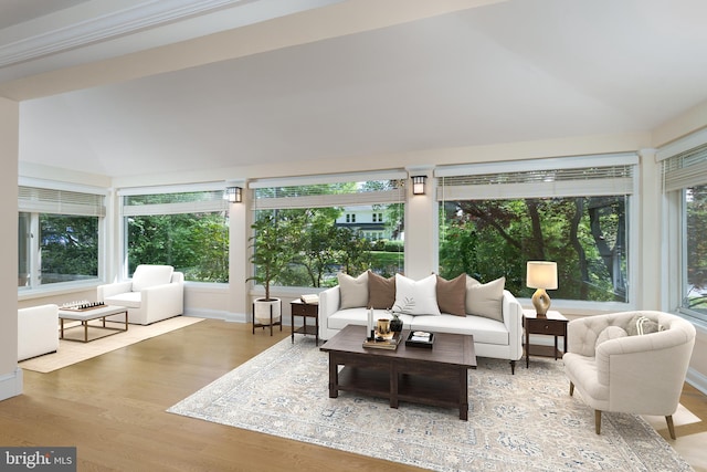 sunroom with lofted ceiling, baseboards, and wood finished floors