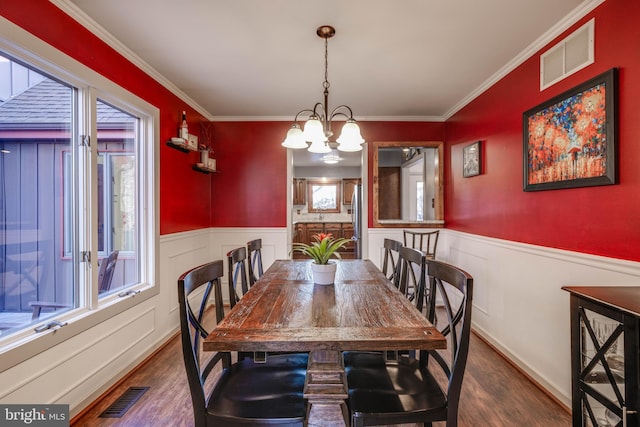 dining room with a wainscoted wall, visible vents, and a notable chandelier