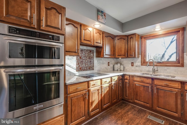 kitchen with black electric cooktop, visible vents, a sink, double oven, and backsplash