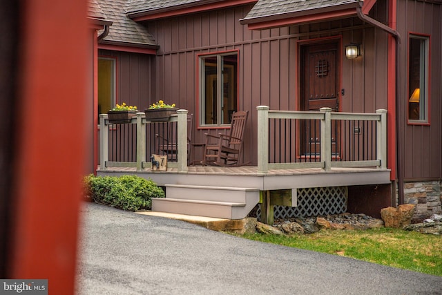 entrance to property with covered porch and a shingled roof