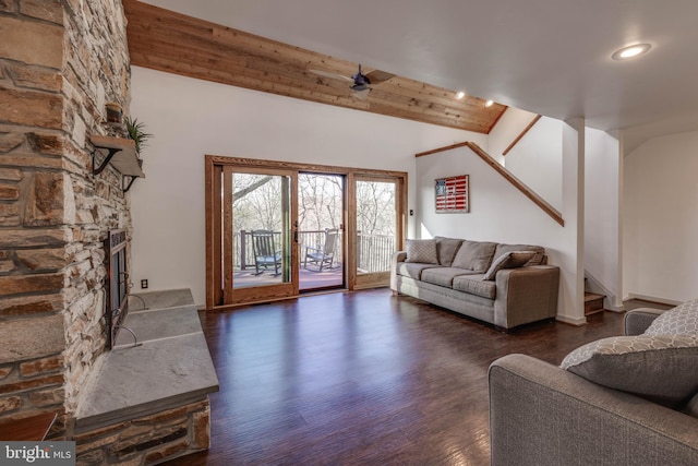 living room featuring dark wood-style flooring, stairway, a stone fireplace, vaulted ceiling, and wooden ceiling