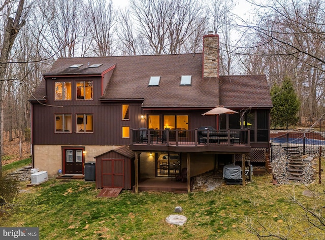rear view of house with an outdoor structure, a shed, a shingled roof, a yard, and a chimney