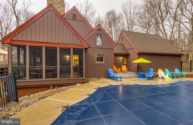 rear view of property featuring a sunroom, fence, a chimney, roof with shingles, and a patio area