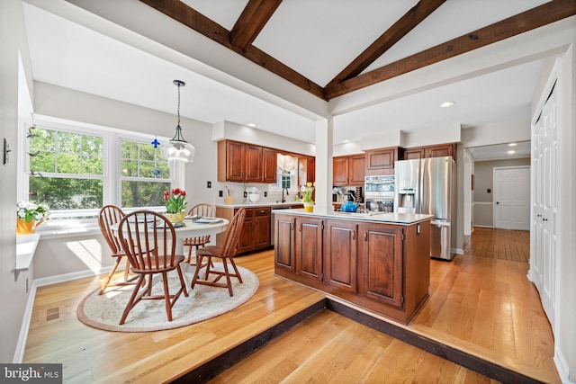 kitchen featuring a center island, light wood-type flooring, light countertops, lofted ceiling with beams, and stainless steel appliances