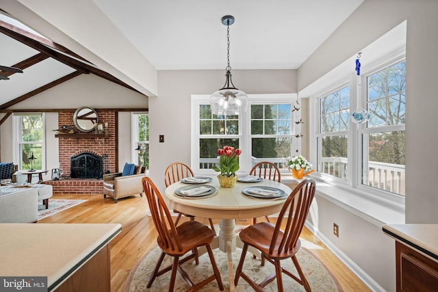 dining space with light wood-type flooring, plenty of natural light, and a fireplace