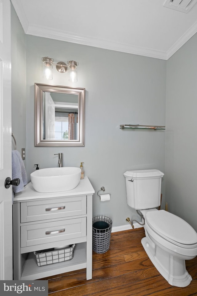half bathroom with baseboards, ornamental molding, wood finished floors, and toilet